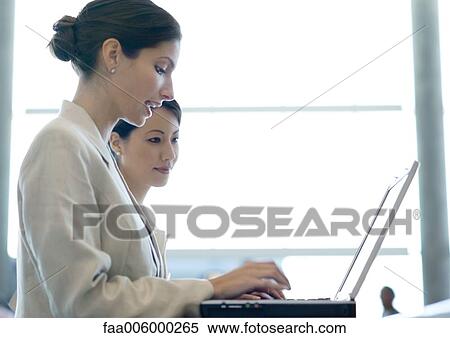 Stock Photography - Businesswomen using laptop together. Fotosearch