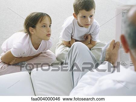 Children looking up at grandfather as he reads newspaper View Large Photo Image Stock Photograph - Children looking up at grandfather as he reads newspaper. Fotosearch