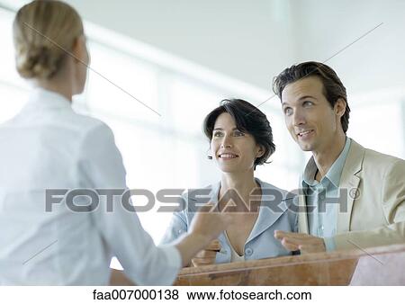 Couple at counter speaking to receptionist View Large Photo Image Stock Photo - Couple at counter speaking to receptionist. Fotosearch