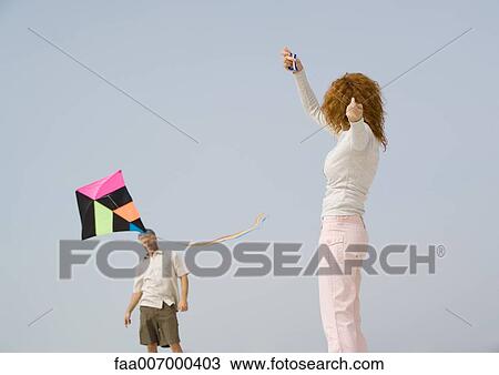 Stock Image - Couple flying kite on beach. Fotosearch
