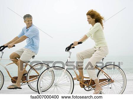 Couple riding bikes on beach View Large Photo Image Stock Image - Couple riding bikes on beach. Fotosearch