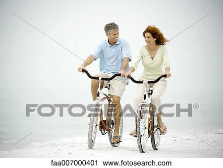 Couple riding bikes on beach View Large Photo Image Stock Image - Couple riding bikes on beach. Fotosearch
