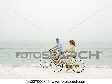 Couple riding bikes on beach View Large Photo Image Stock Photograph - Couple riding bikes on beach. Fotosearch