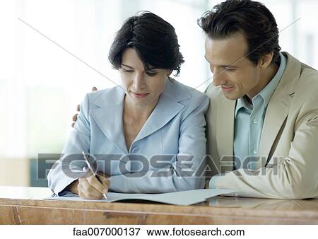 Stock Photo - Couple signing document at counter. Fotosearch