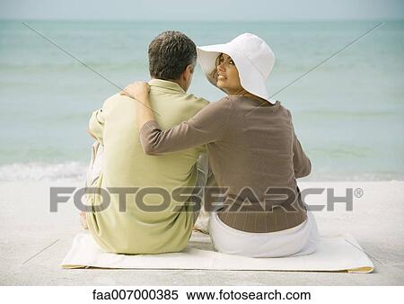 Couple sitting on beach, rear view View Large Photo Image Stock Photography - Couple sitting on beach, rear view. Fotosearch