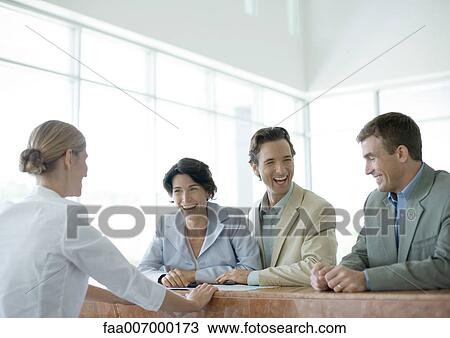 Stock Image - Customers standing at counter, laughing. Fotosearch