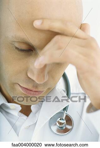 Stock Image - Doctor holding head and looking down. Fotosearch