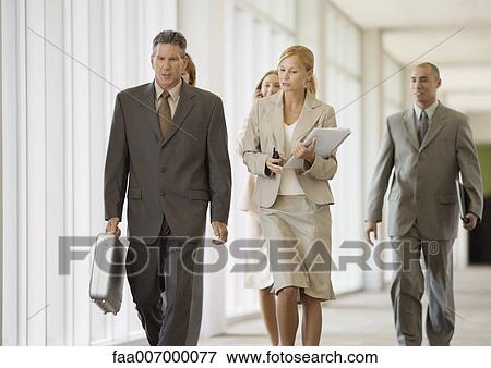 Executives walking through corridor of office building View Large Photo Image Stock Photo - Executives walking through corridor of office building. Fotosearch