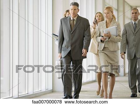 Executives walking through corridor of office building View Large Photo Image Stock Photo - Executives walking through corridor of office building. Fotosearch