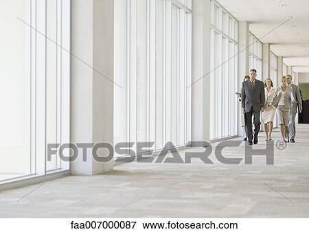Stock Photo - Executives walking through corridor of office building. Fotosearch