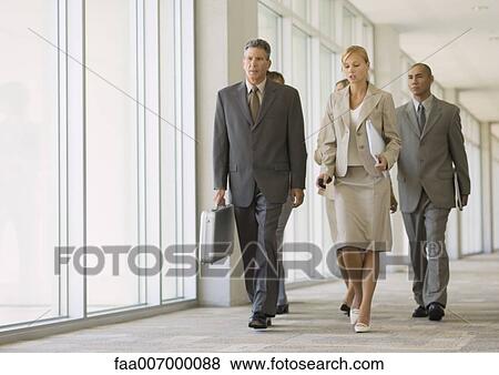 Executives walking through corridor of office building View Large Photo Image Stock Photo - Executives walking through corridor of office building. Fotosearch