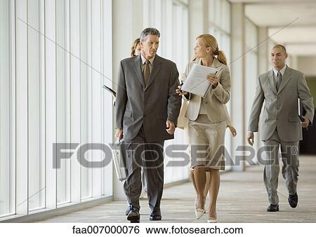 Stock Photograph - Executives walking through corridor of office building. Fotosearch