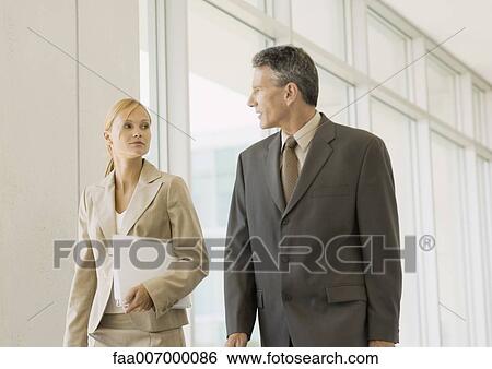 Executives walking through corridor of office building View Large Photo Image Stock Photograph - Executives walking through corridor of office building. Fotosearch