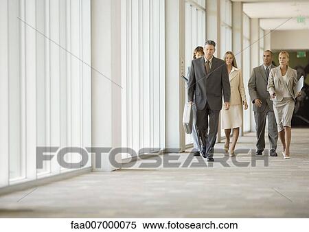 Stock Photography - Executives walking through corridor of office building. Fotosearch
