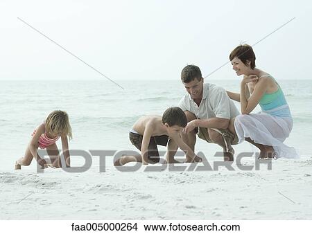 Family at the beach, children playing on sand while parents watch View Large Photo Image Picture - Family at the beach, children playing on sand while parents watch. Fotosearch