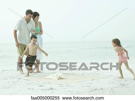 Stock Photography - Family at the beach, children running around beach mat. Fotosearch