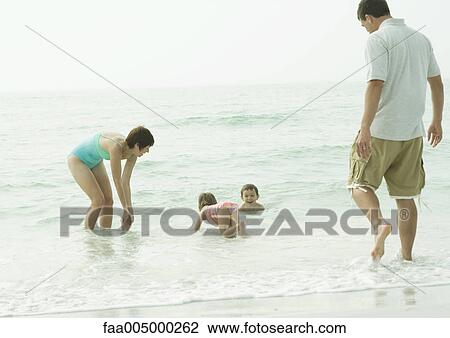 Family at the beach, playing in the water View Large Photo Image Stock Image - Family at the beach, playing in the water. Fotosearch