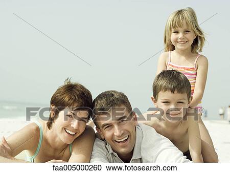 Stock Image - Family lying on beach, smiling, portrait. Fotosearch