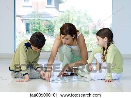 Stock Image - Family putting together puzzle. Fotosearch