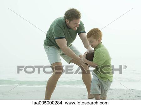 Father and son fighting for ball on beach View Large Photo Image Picture - Father and son fighting for ball on beach. Fotosearch
