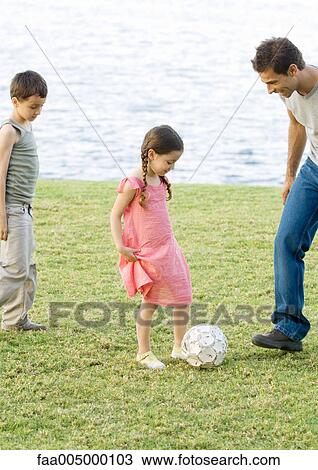 Stock Image - Father playing soccer with children. Fotosearch