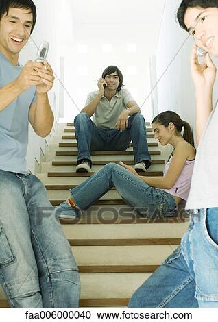 Four young people using cell phones in stairway View Large Photo Image Stock Image - Four young people using cell phones in stairway. Fotosearch