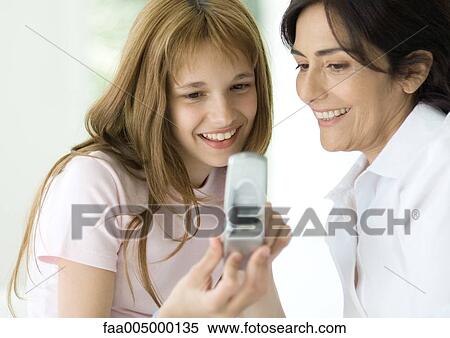 Girl and mature woman looking at cell phone together View Large Photo Image Stock Photography - Girl and mature woman looking at cell phone together. Fotosearch