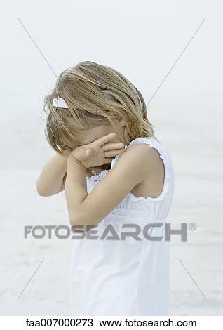 Stock Image - Girl covering face on beach. Fotosearch