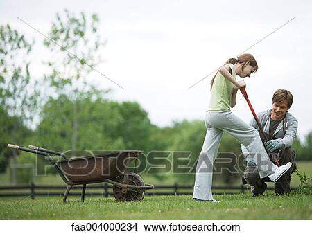 Girl digging in yard while man watches nearby View Large Photo Image Picture - Girl digging in yard while man watches nearby. Fotosearch