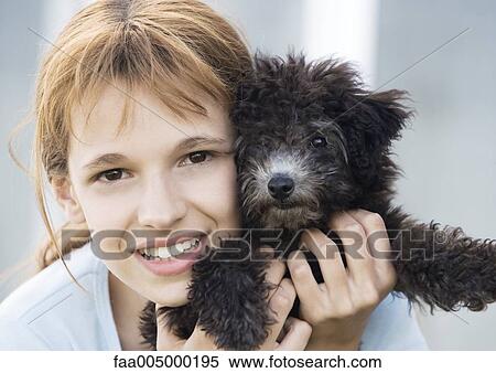 Girl holding puppy up next to face, portrait View Large Photo Image Stock Photography - Girl holding puppy up next to face, portrait. Fotosearch