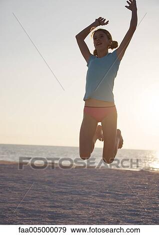 Stock Photo - Girl jumping on beach. Fotosearch