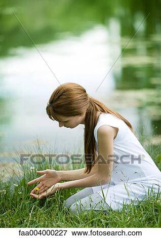 Girl kneeling in grass with hands cupped View Large Photo Image Stock Photo - Girl kneeling in grass with hands cupped. Fotosearch