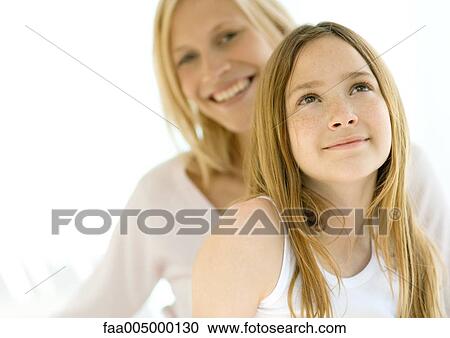 Stock Image - Girl looking up, mother in background. Fotosearch