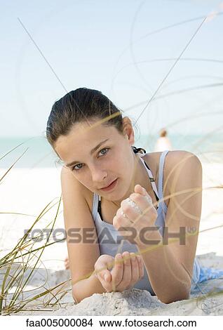 Girl lying on beach, letting sand run through hands View Large Photo Image Picture - Girl lying on beach, letting sand run through hands. Fotosearch