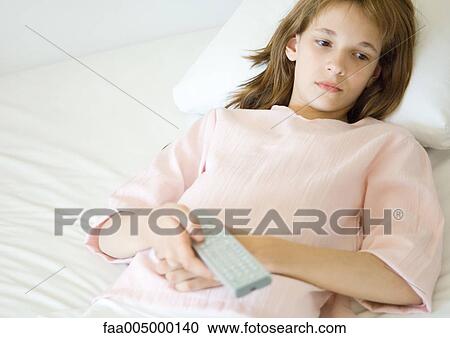 Girl reclining on sofa, pointing remote control View Large Photo Image Stock Image - Girl reclining on sofa, pointing remote control. Fotosearch