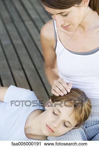 Stock Image - Girl sleeping with head on mother's lap. Fotosearch