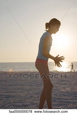 Girl standing on beach, runner in background View Large Photo Image Stock Photo - Girl standing on beach, runner in background. Fotosearch