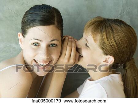 Stock Photo - Girl whispering into young woman's ear. Fotosearch