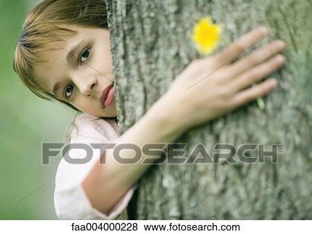 Girl with arm around tree, holding flower View Large Photo Image Stock Photo - Girl with arm around tree, holding flower. Fotosearch