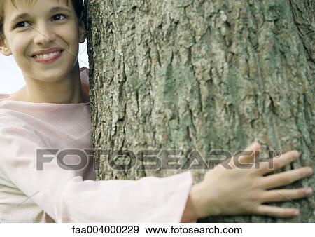 Girl with arm around tree, smiling View Large Photo Image Stock Photo - Girl with arm around tree, smiling. Fotosearch