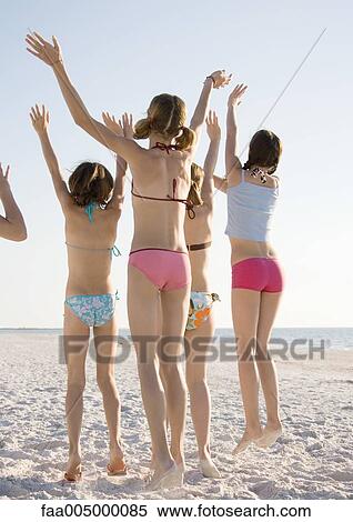 Girls jumping and waving on beach, rear view View Large Photo Image Stock Photography - Girls jumping and waving on beach, rear view. Fotosearch