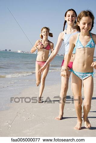 Stock Photo - Girls running and walking on beach. Fotosearch