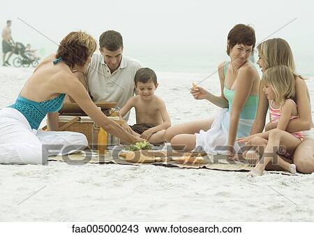 Stock Image - Group having picnic on beach. Fotosearch