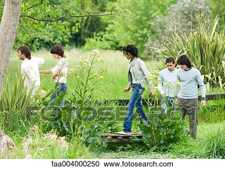 Group of young adult friends walking in park View Large Photo Image Stock Image - Group of young adult friends walking in park. Fotosearch