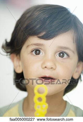 Stock Photo - Little boy holding bubble wand, portrait. Fotosearch