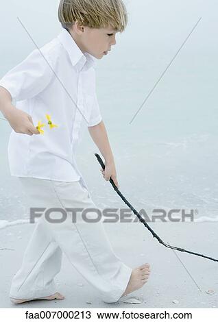 Little boy walking alongside surf on beach, holding flowers in one hand and stick in the other View Large Photo Image Stock Image - Little boy walking alongside surf on beach, holding flowers in one hand and stick in the other. Fotosearch