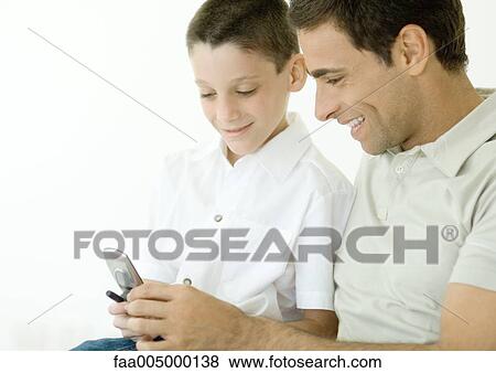 Stock Photo - Man and son looking at cell phone together. Fotosearch