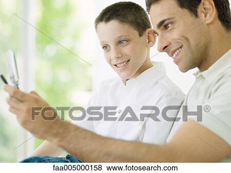 Man and son looking at cell phone View Large Photo Image Stock Photo - Man and son looking at cell phone. Fotosearch