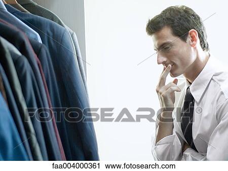 Man choosing jacket from closet View Large Photo Image Stock Image - Man choosing jacket from closet. Fotosearch