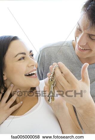Stock Photo - Man handing woman keys, woman smiling. Fotosearch